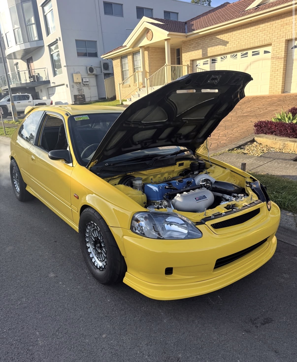 Yellow Honda Civic with the bonnet up during paint preparation at Sydney Detail District